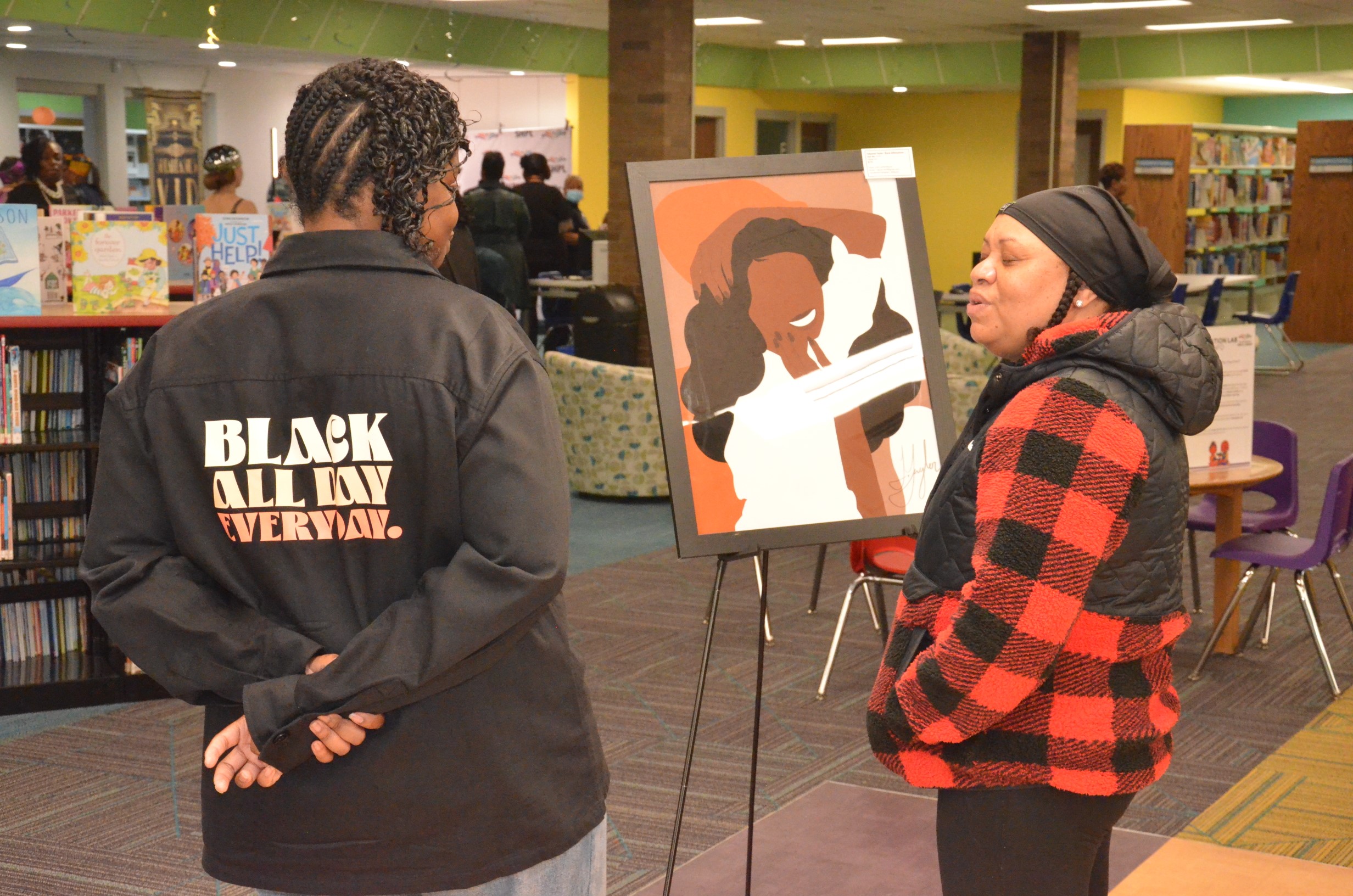 Two patrons looking at art during the Wakanda Night event