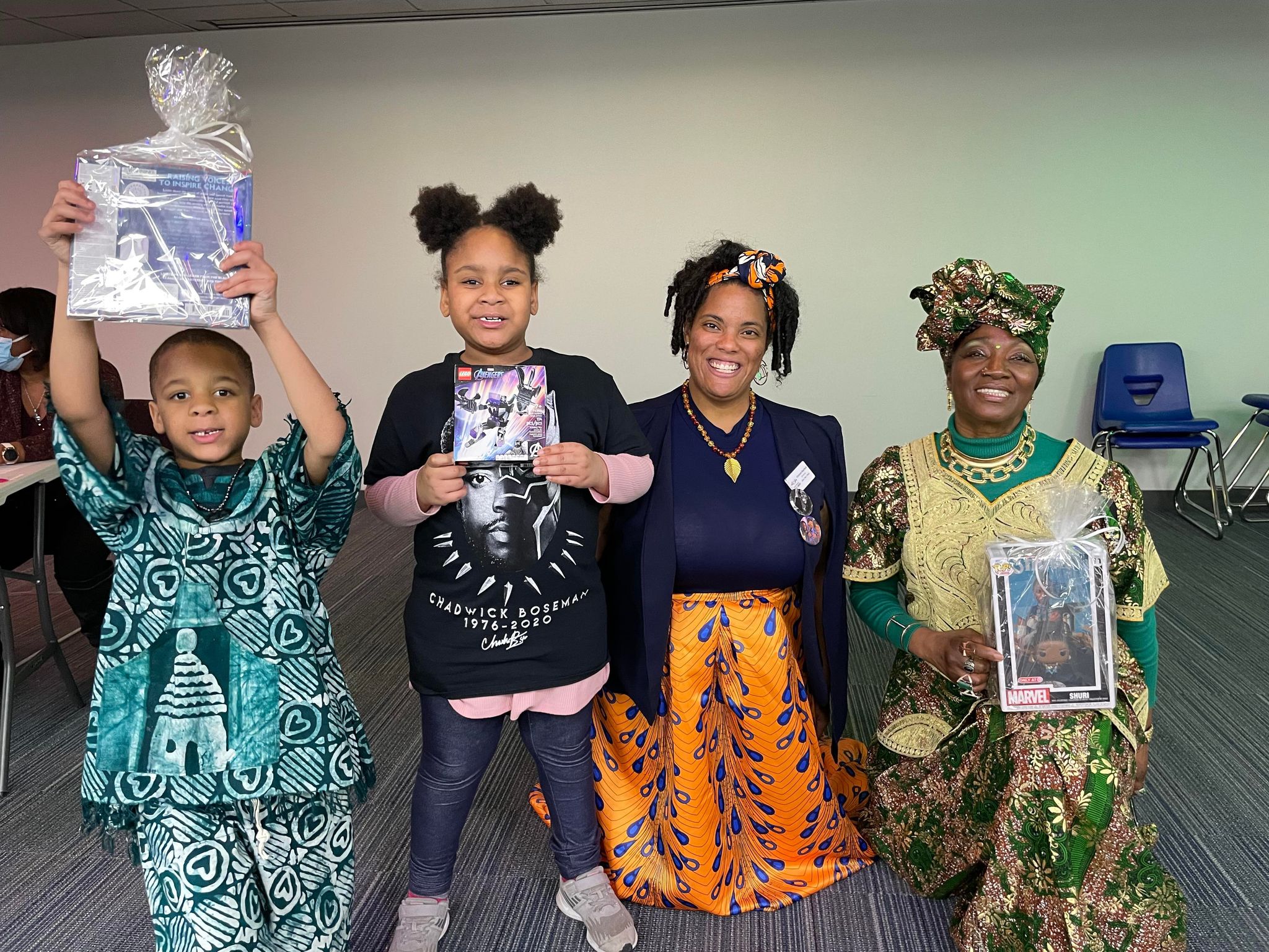 Two children posing with their goody bags and prizes with two presenters during the Wakanda Night event