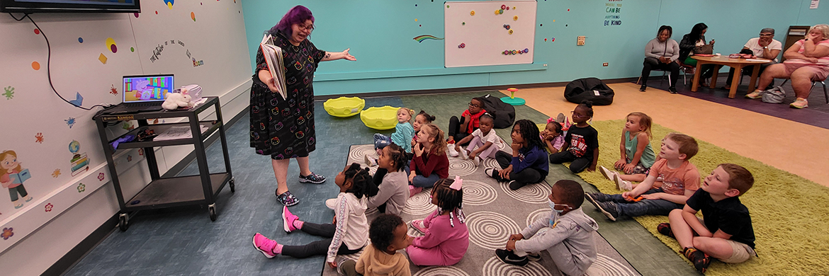 Librarian reading animatedly to a group of children