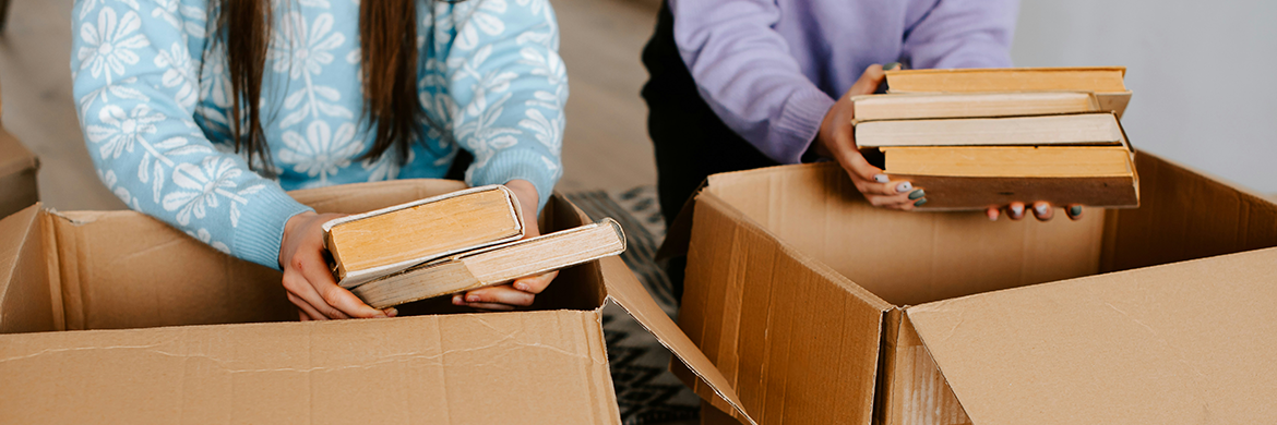 Two girls sorting through books and putting them in boxes