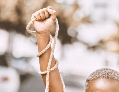 An African American Female holding her fist up with a rope wrapped around her arm