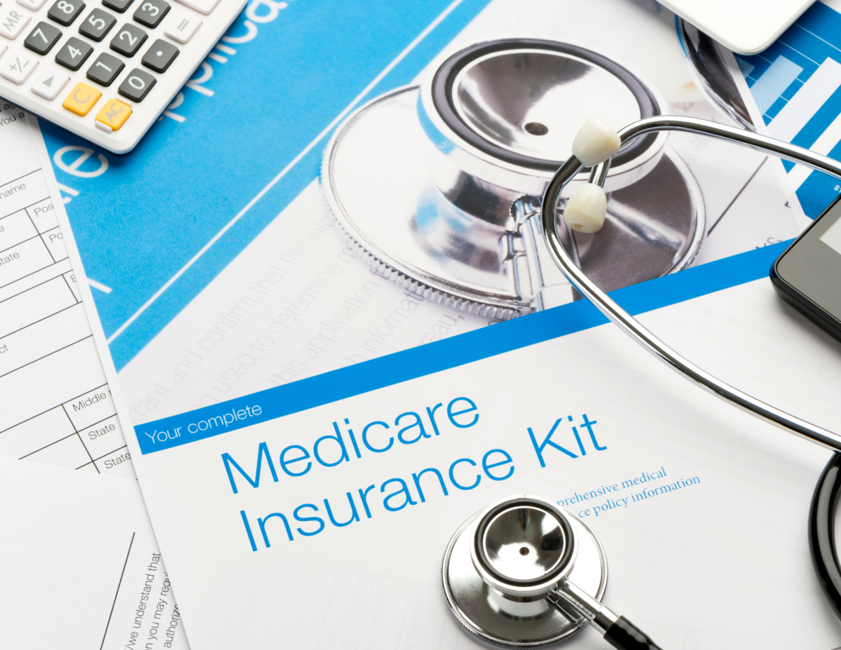 A book that says, "Medicare Insurance Kit" with a stethoscope and a calculator on top.