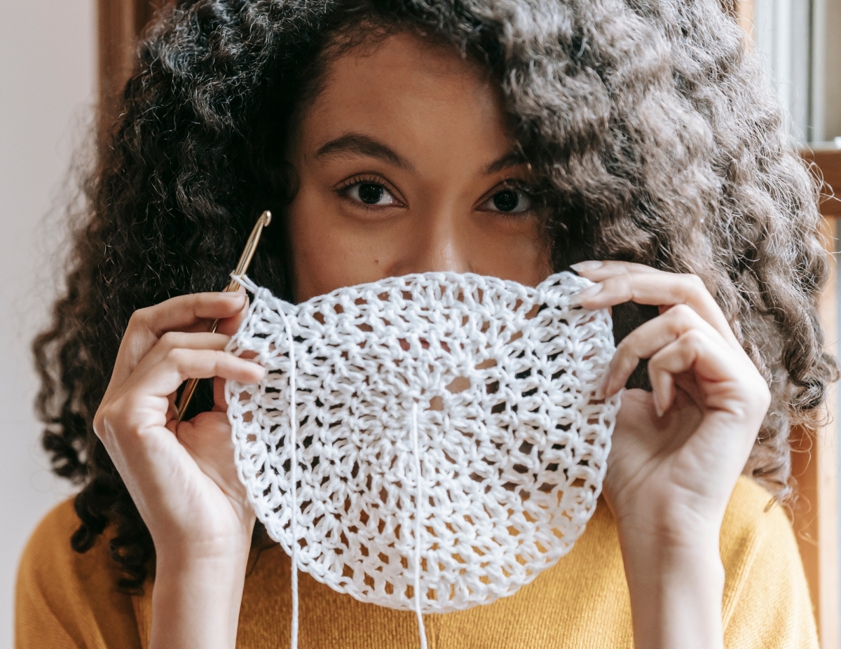 A women holding up material that she has crocheted into a circle. 