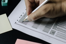 Hand filling in answer bubbles on a paper test